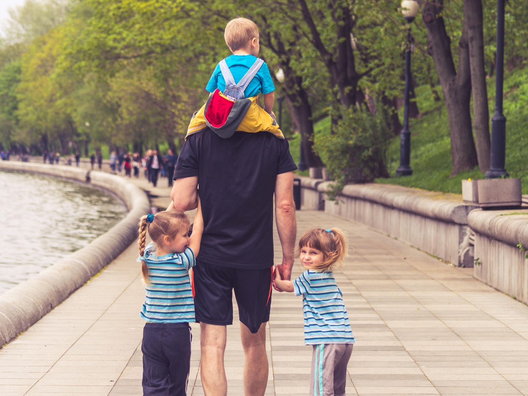 Photo of a man walking in the park with his three children
