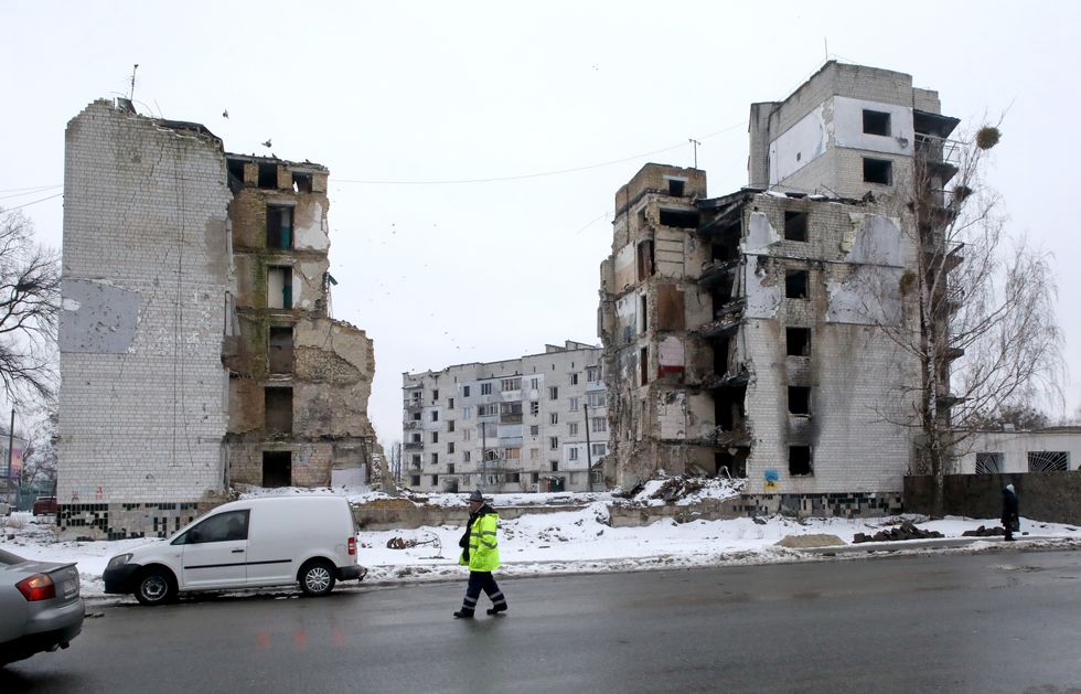 Photo of a man walking past a multi-storey building destroyed by Russian shelling in Borodianka, near Kyiv.