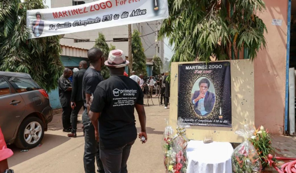 Photo of a man walking past a poster of a memorial for slain journalist Martinez Zogo