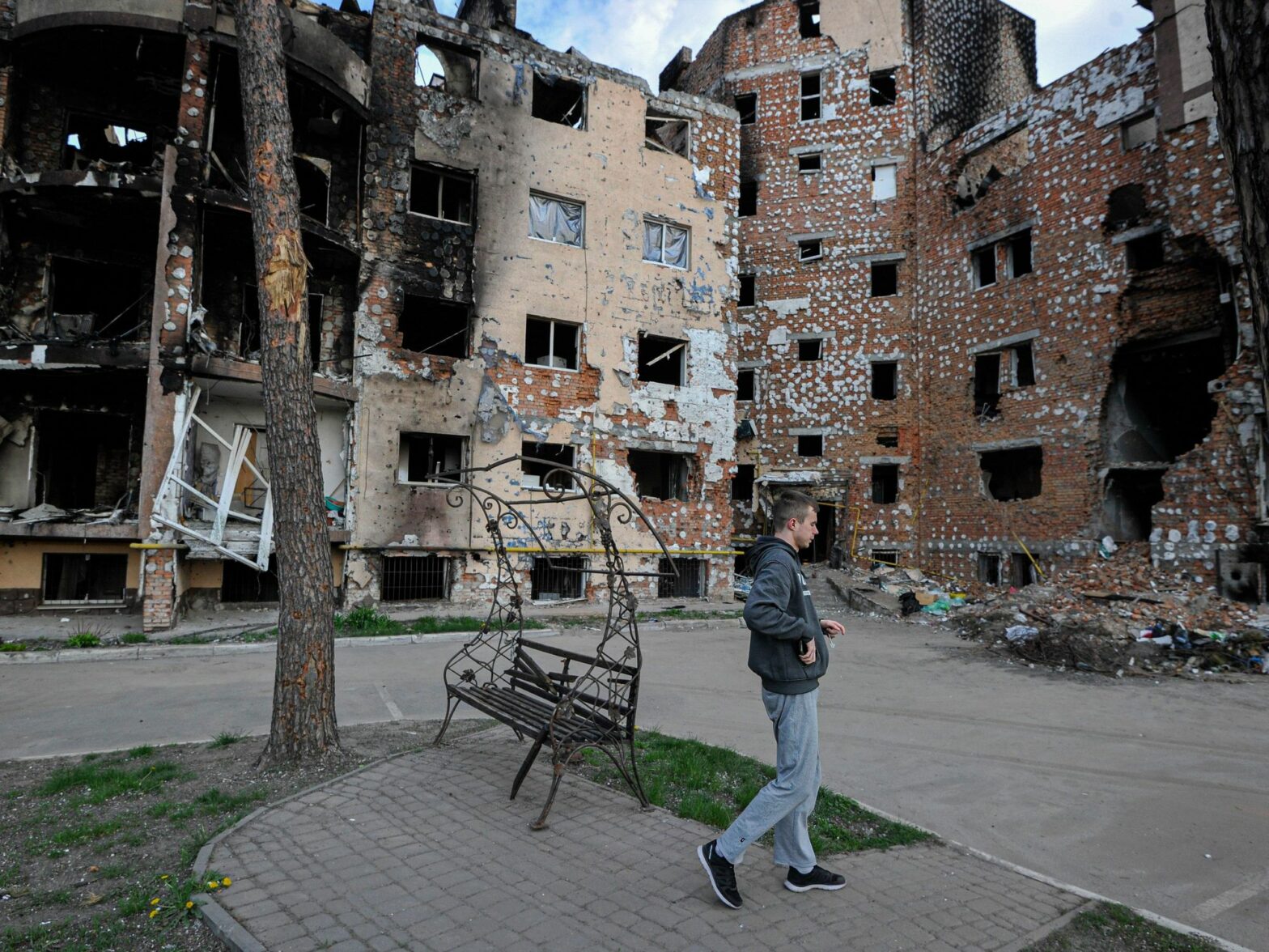 Photo of a man walking past destroyed houses in Irpin