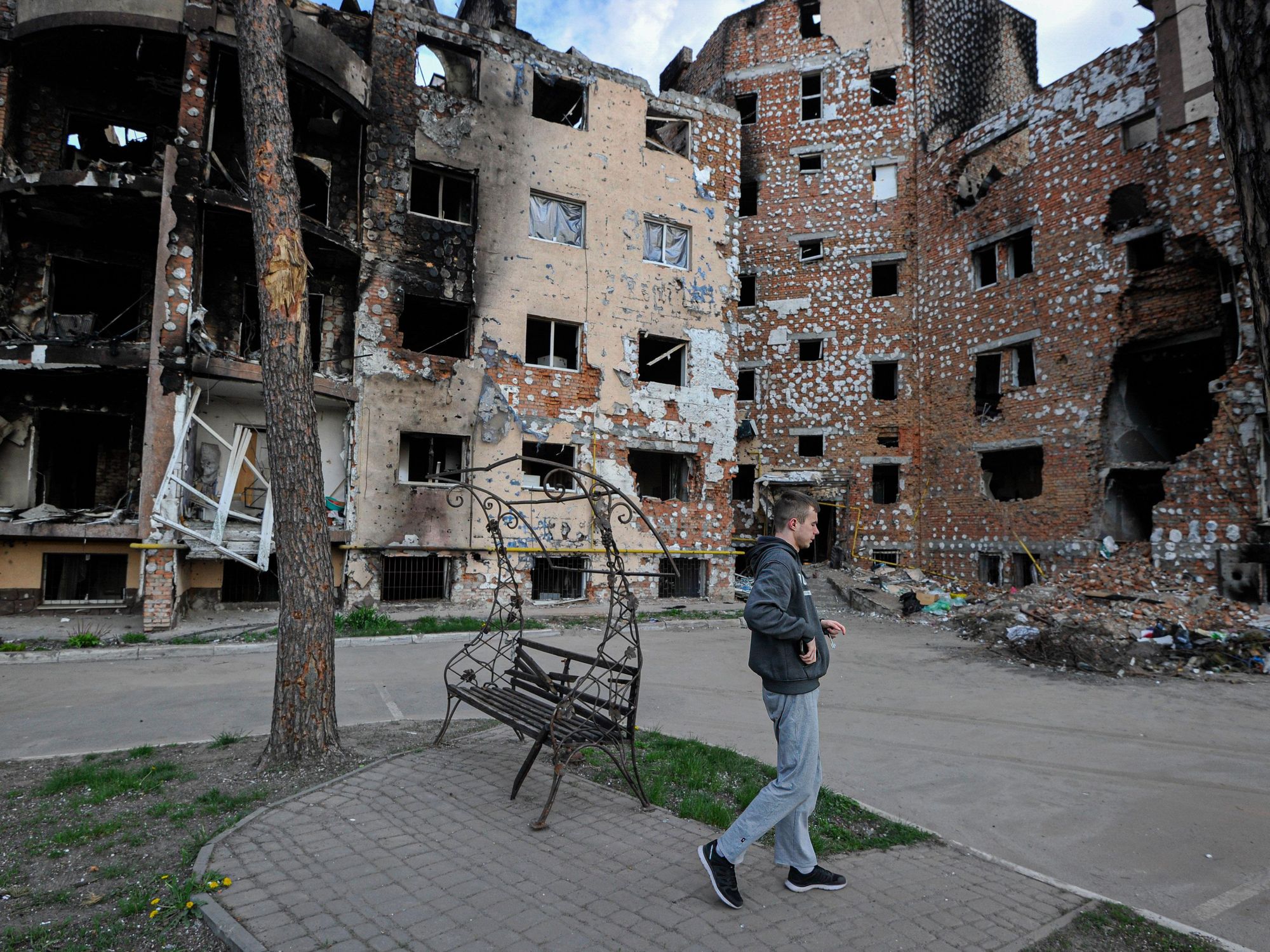 Photo of a man walking past destroyed houses in Irpin
