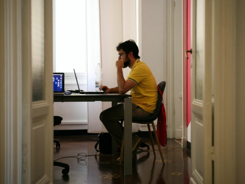 Photo of a man wearing a soccer jersey working on his computer at home