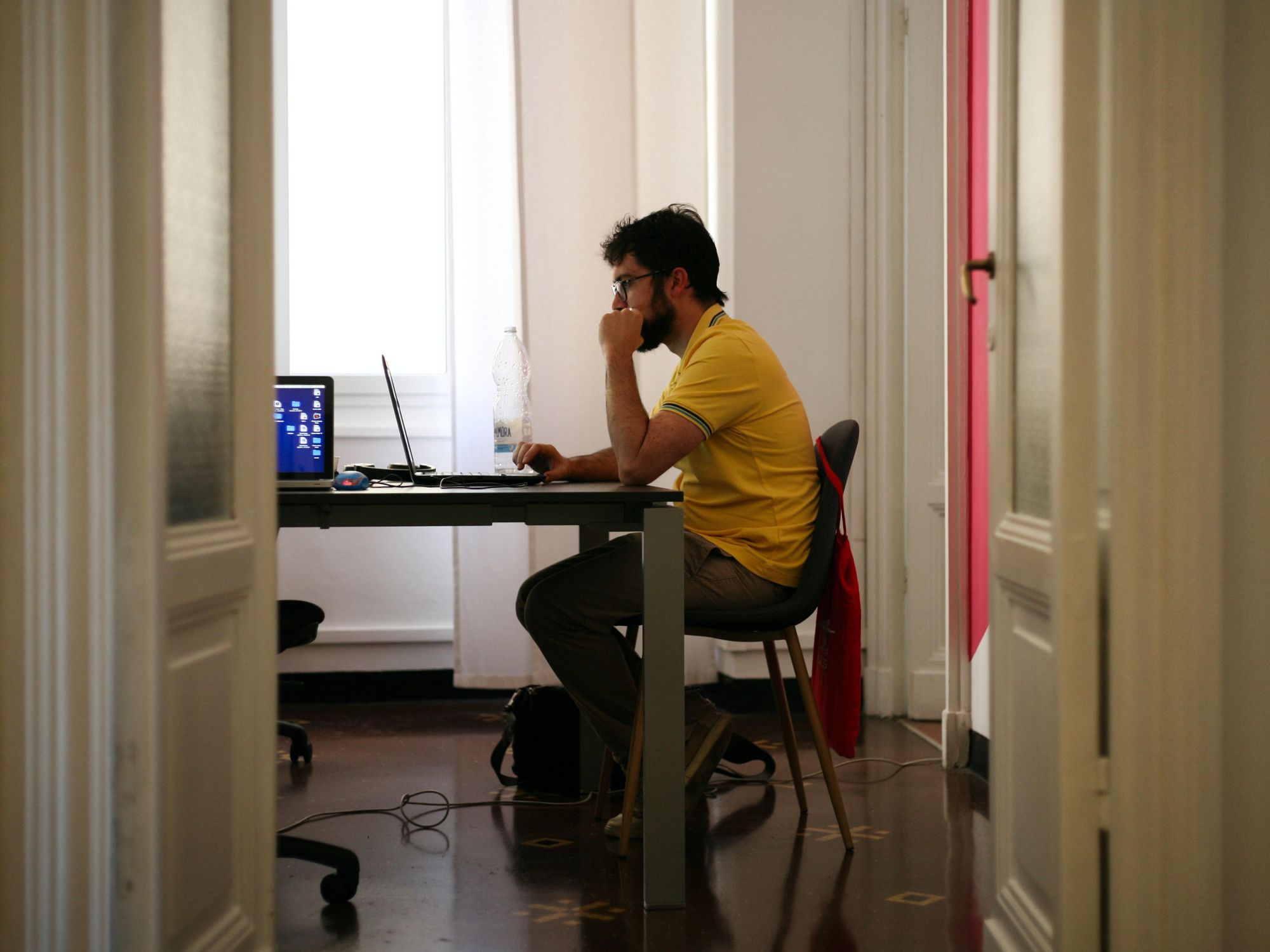 Photo of a man wearing a soccer jersey working on his computer at home