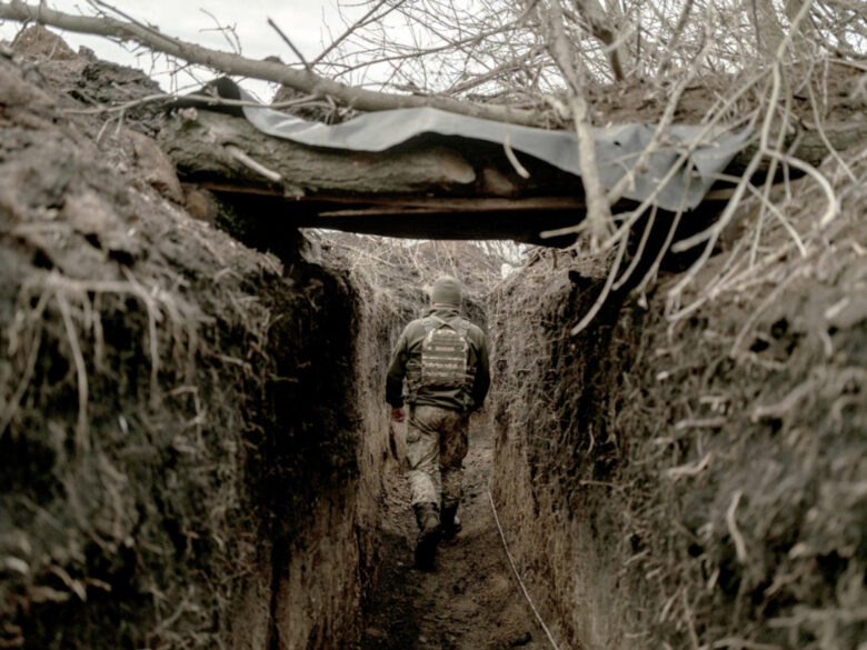 Photo of a member of Ukraine's 72nd Brigade walking in a trench, walking away from the camera