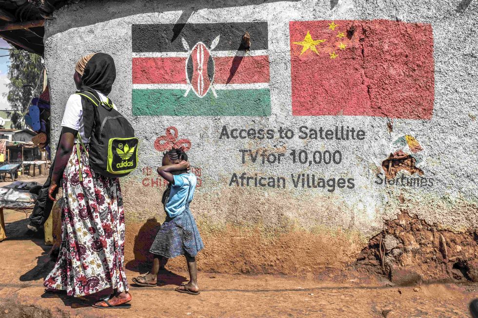 Photo of a mother and a child walking past a drawing of the Chinese digital Tv Company in partnership with Kenya