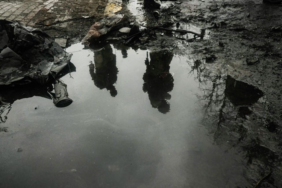 Photo of a mud puddle and reflections of two men