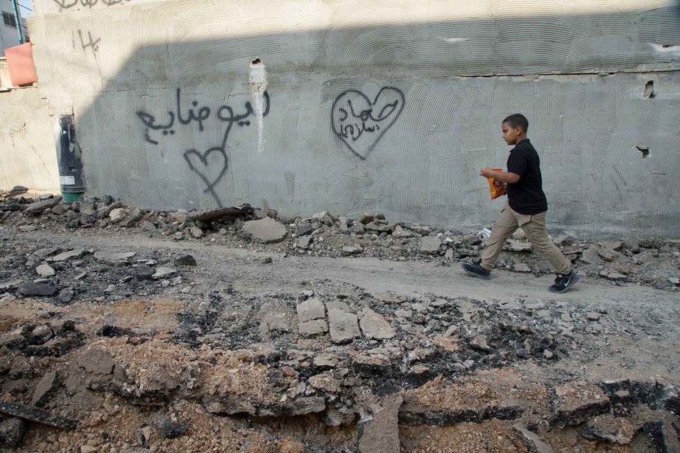 Photo of a Palestinian boy walking through a destroyed road after clashes during an Israeli raid at Jenin refugee camp.