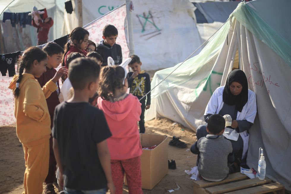 Photo of a Palestinian doctor treating a child in the Rafah camps
