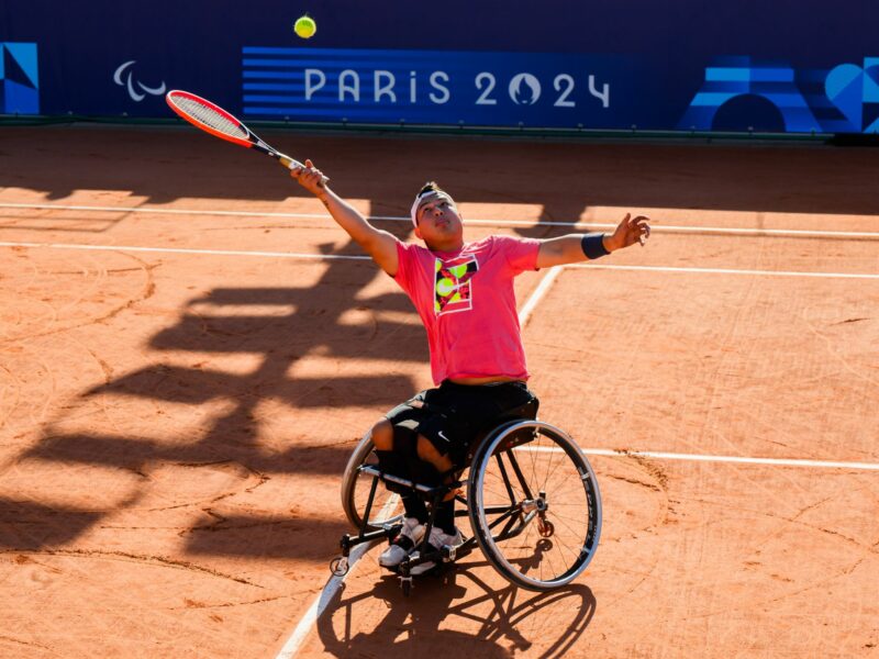Photo of a Paralympic tennis player hitting a ball above his head while in a wheelchair in Paris