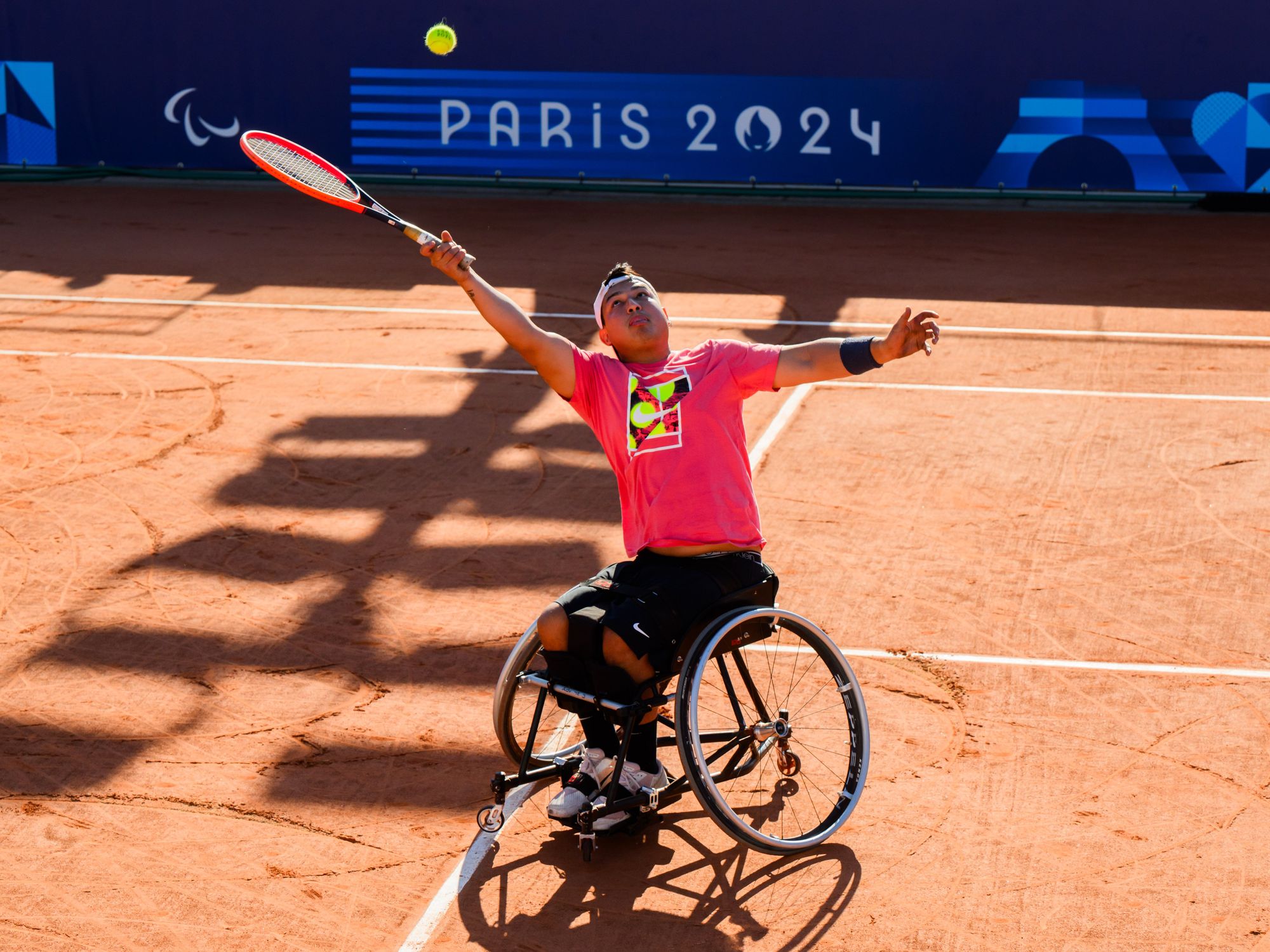 Photo of a Paralympic tennis player hitting a ball above his head while in a wheelchair in Paris