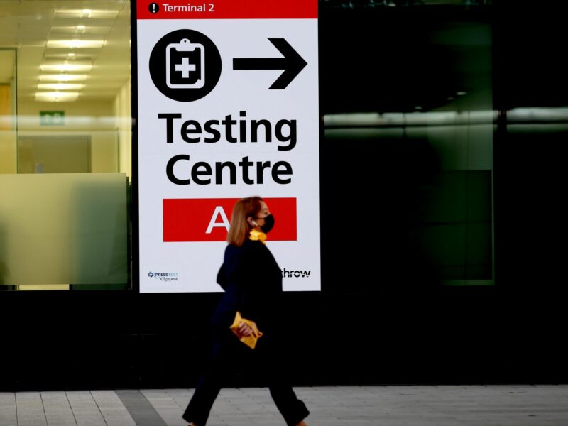 Photo of a passenger walking past a sign indicating the testing center in Heathrow Airport in London.