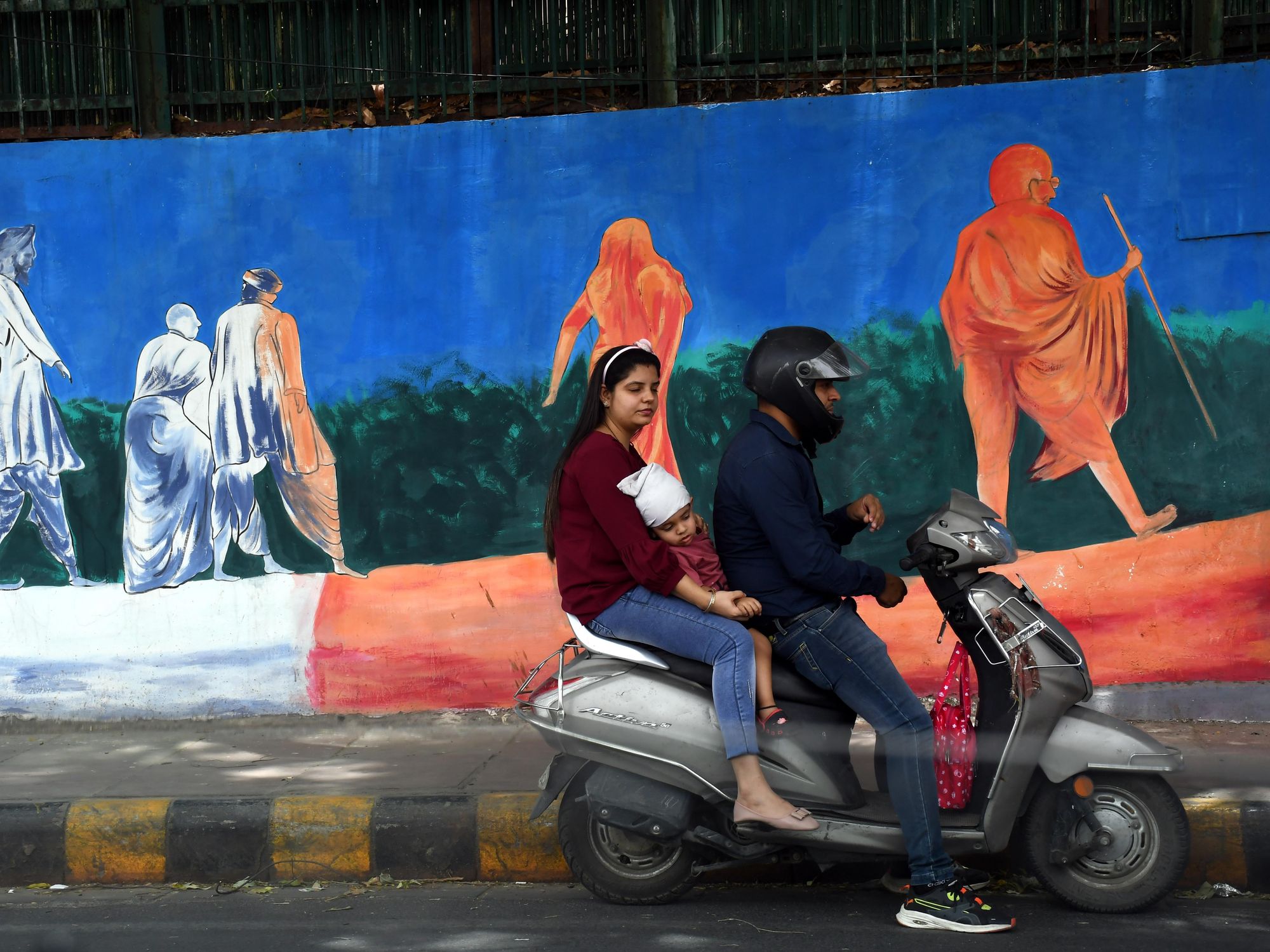 Photo of a people in front of a Gandhi mural in New Delhi