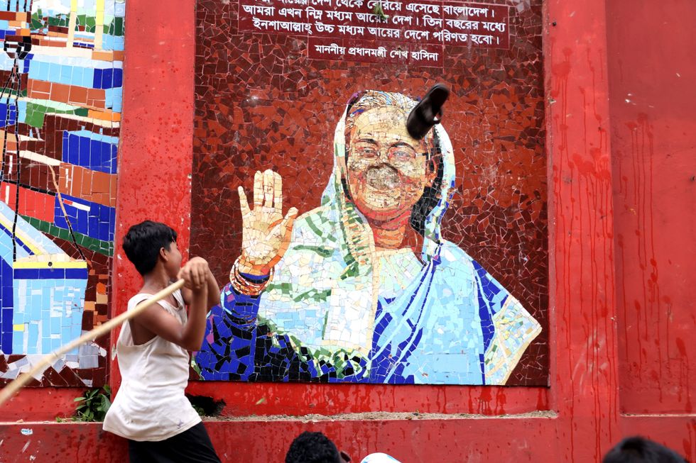 Photo of a person breaking Sheikh Hasina's mural in Laldighi area