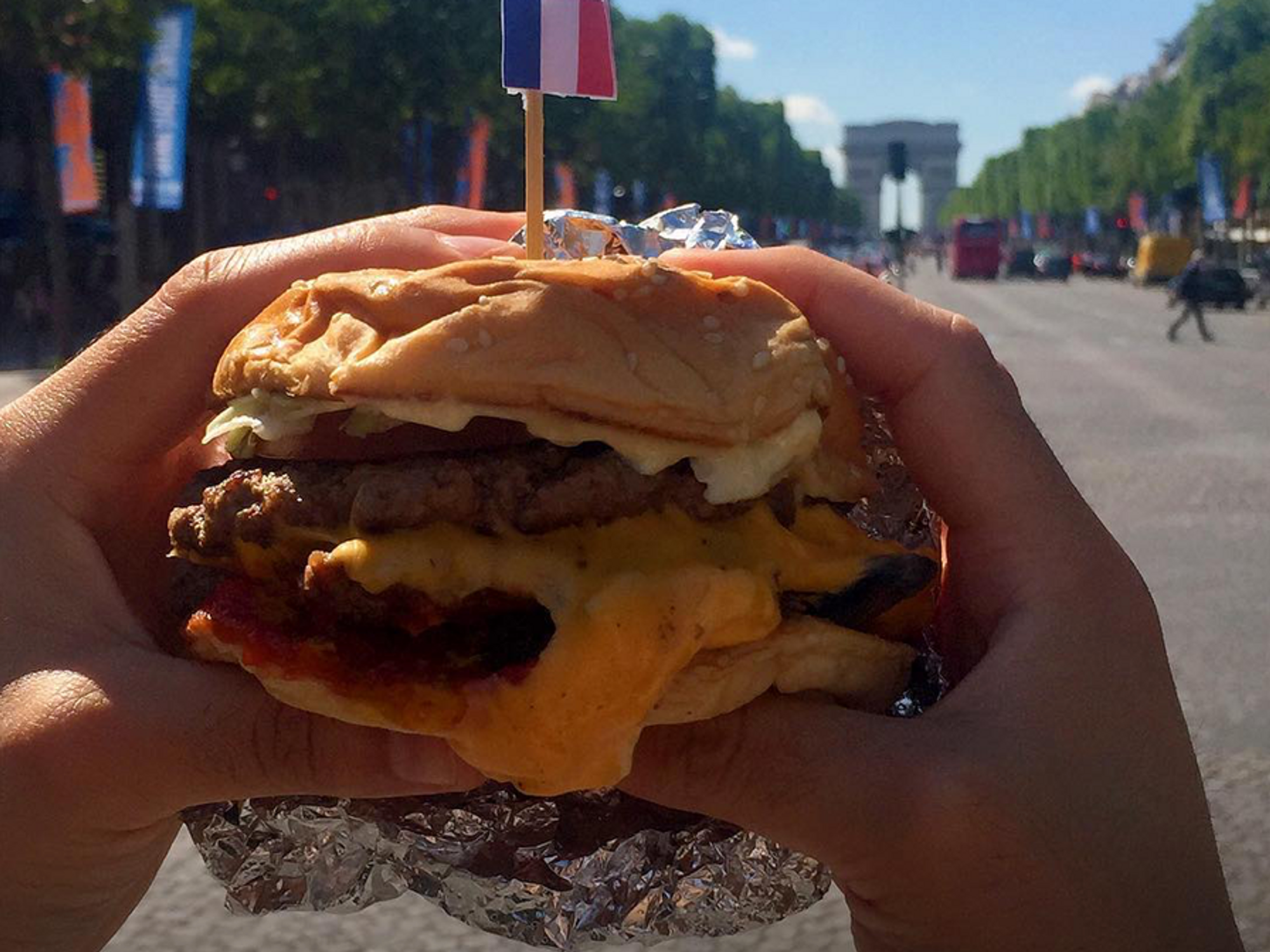 Photo of a person holding a hamburger on the Champs Elysées