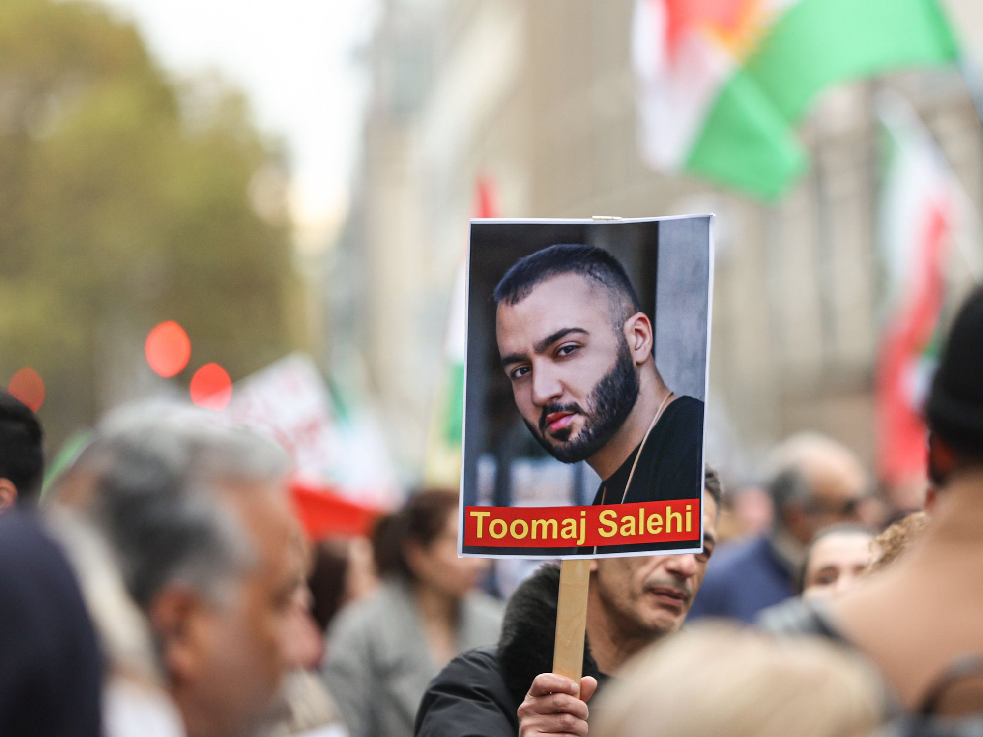 Photo of a person holding a placard showing Iranian rapper Toomaj Salehi as part of a protest in Cologne, Germany