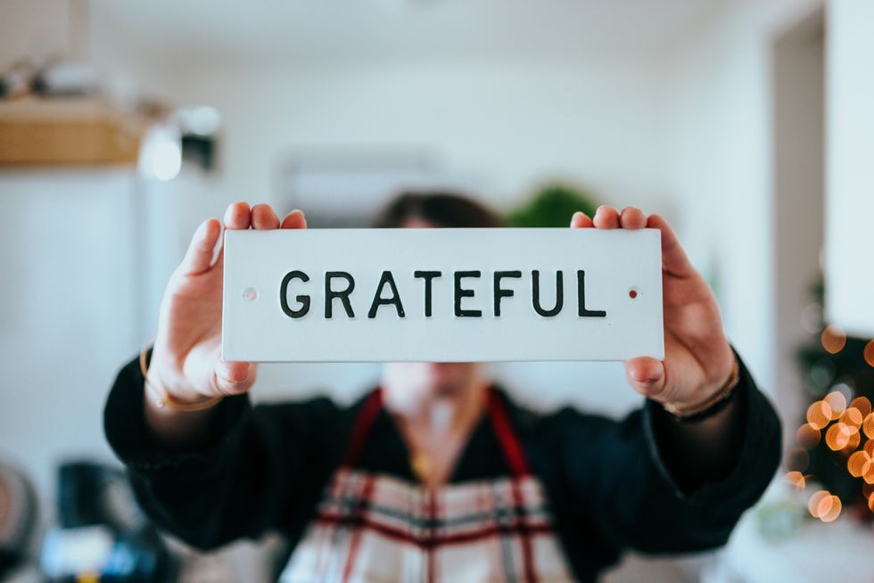 Photo of a person holding a sign reading GRATEFUL