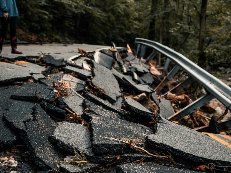Photo of a person standing next to rubble of a road destroyed by an earthquake