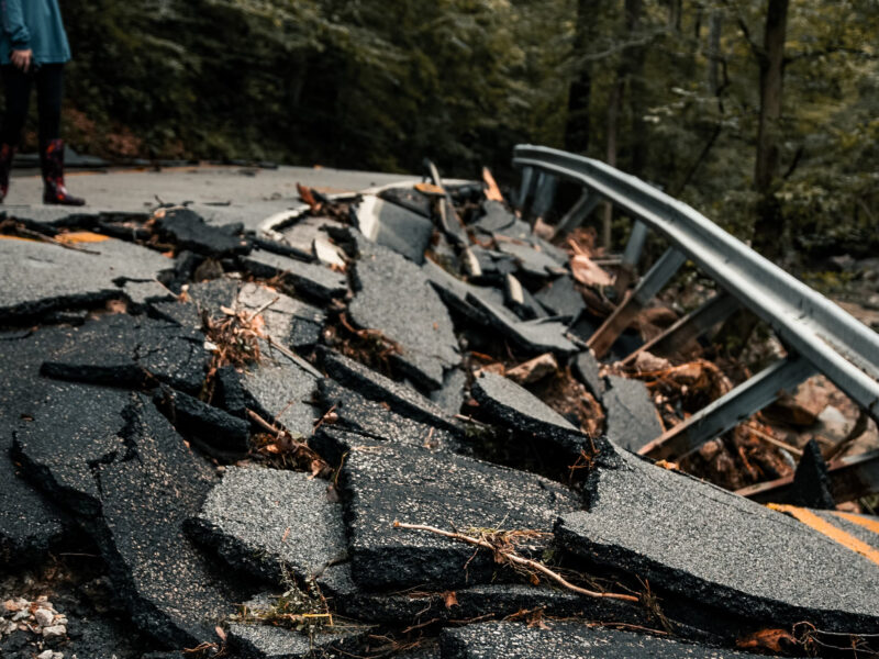 Photo of a person standing next to rubble of a road destroyed by an earthquake