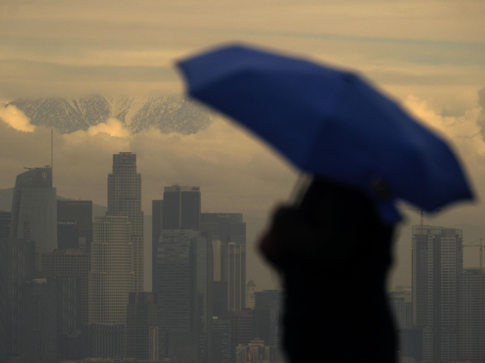 Photo of a person under an umbrella looking over the Los Angeles cityscape
