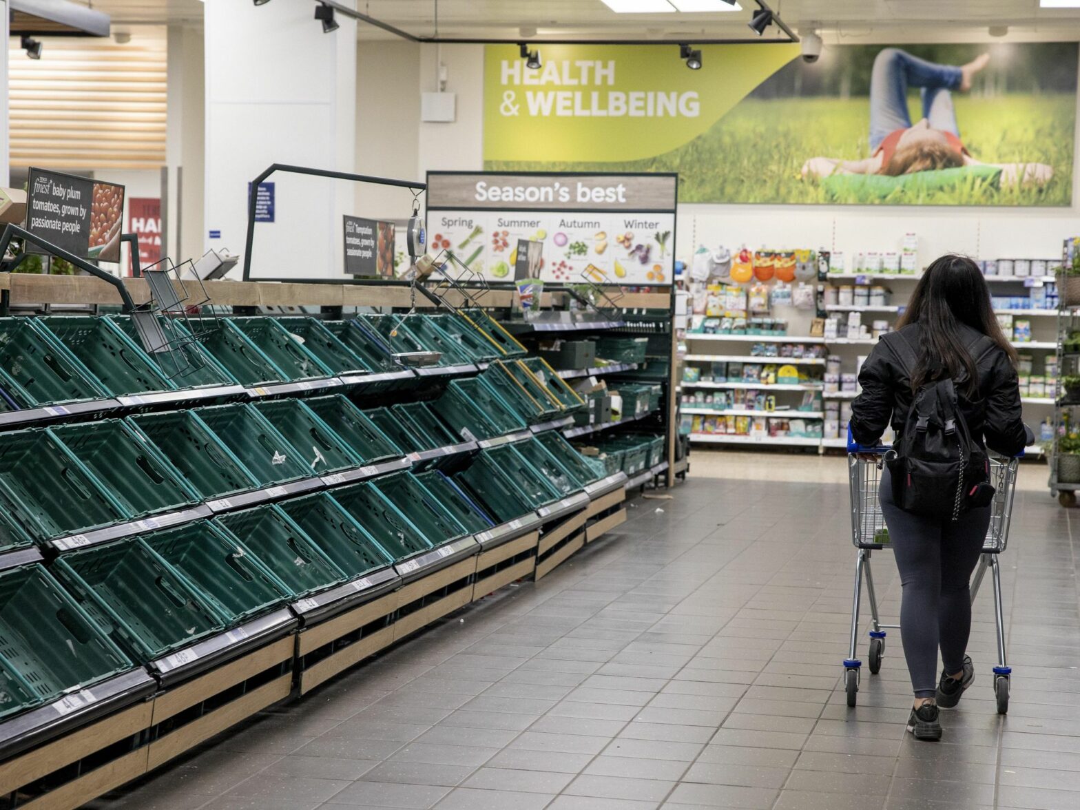 Photo of a person walking in a supermarket with empty shelves