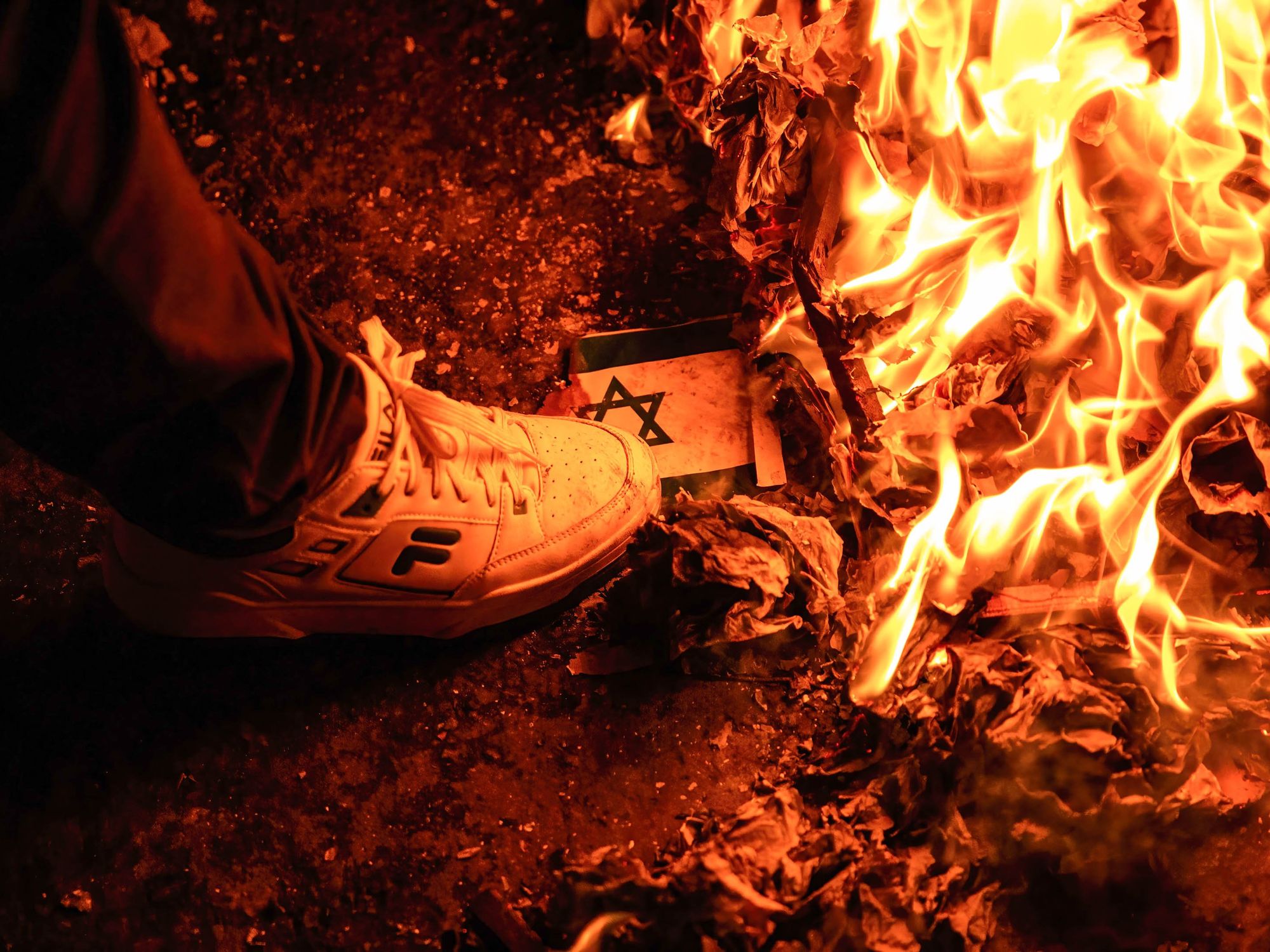 Photo of a person wearing sneakers stomping on a burning Israeli flag during a pro-Palestinian demonstration in Bogota, Colombia, on Oct. 17