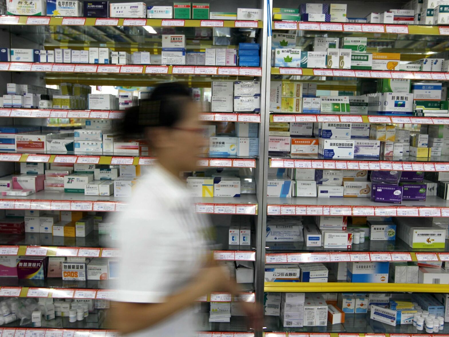 Photo of a pharmarcist walking past shelves with medication in Yucheng, northern China
