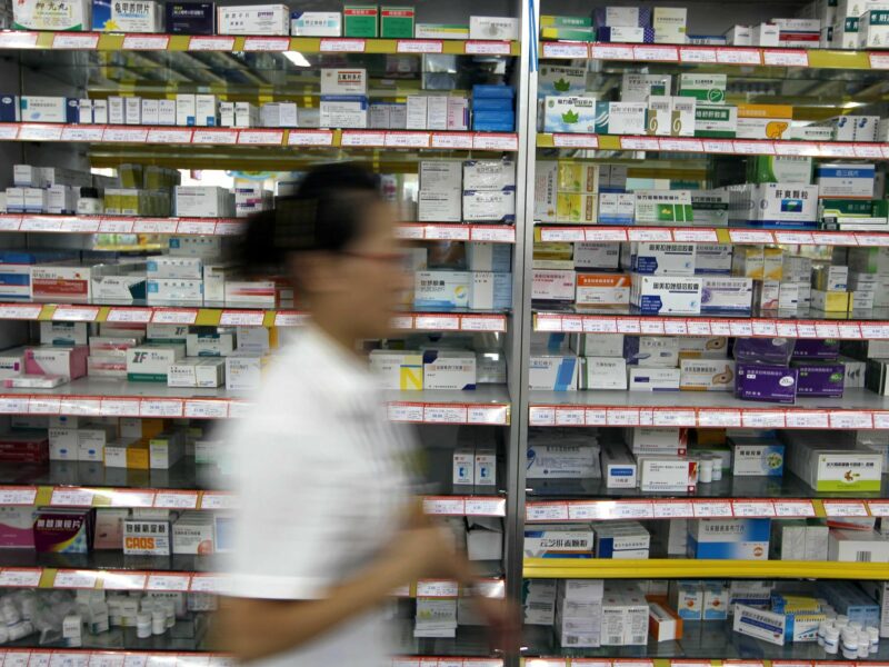 Photo of a pharmarcist walking past shelves with medication in Yucheng, northern China