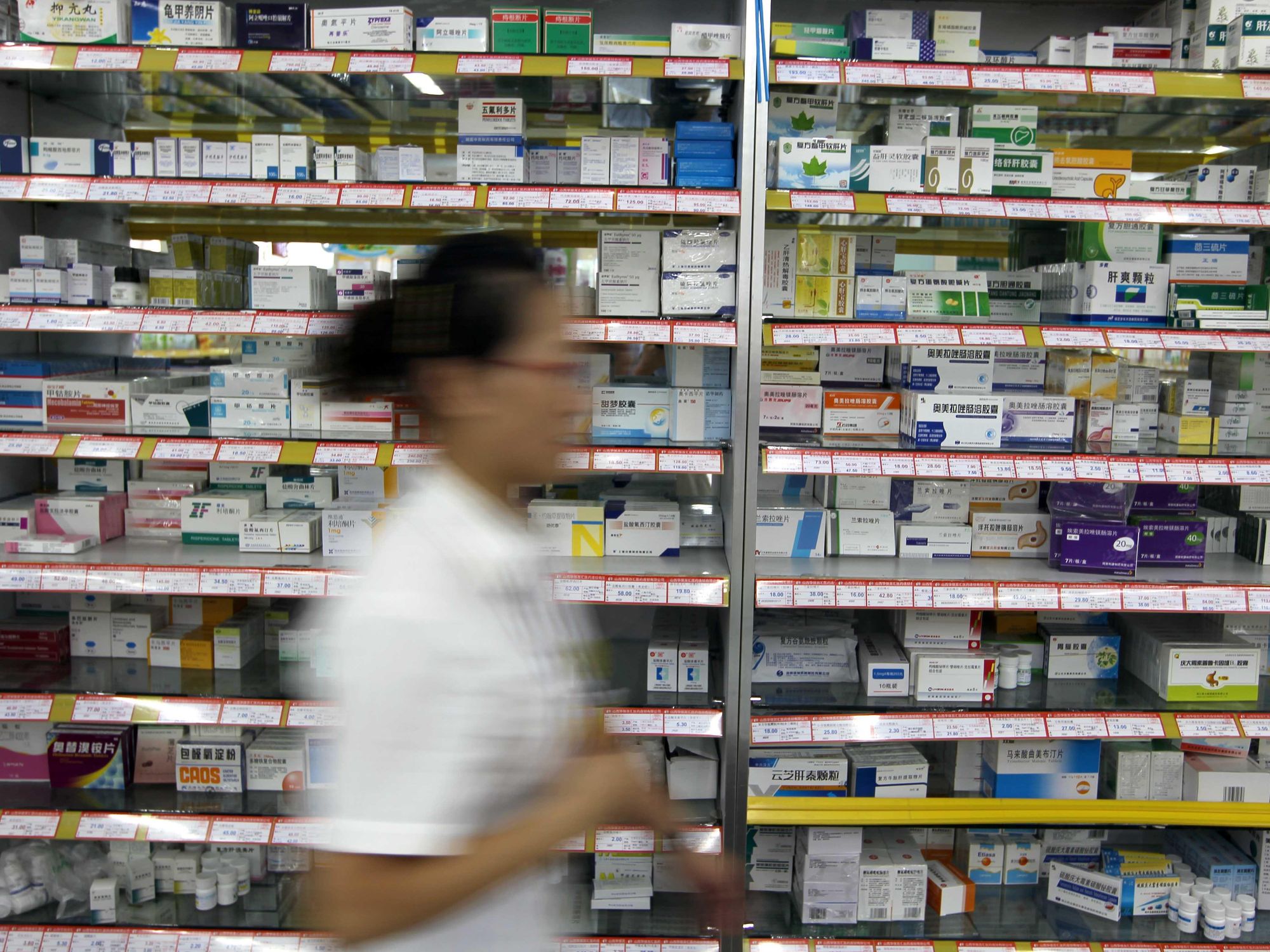Photo of a pharmarcist walking past shelves with medication in Yucheng, northern China