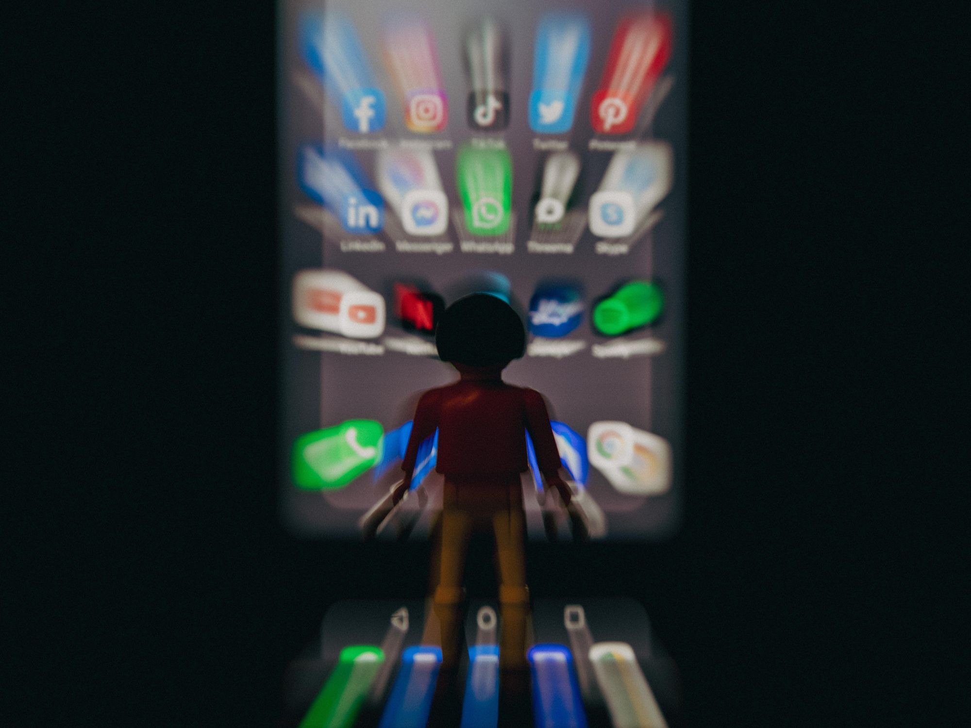 Photo of a plastic figurine in front of a smartphone displaying social media icons