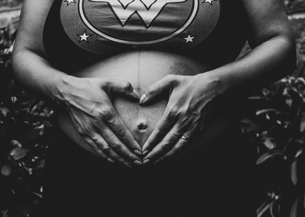 Photo of a pregnant woman placing her hands in a heart shape on her belly