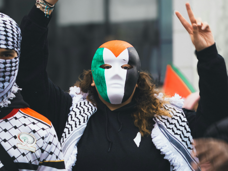 Photo of a pro-Palestinian protester wearing a mask with the flag of Palestine painted on it
