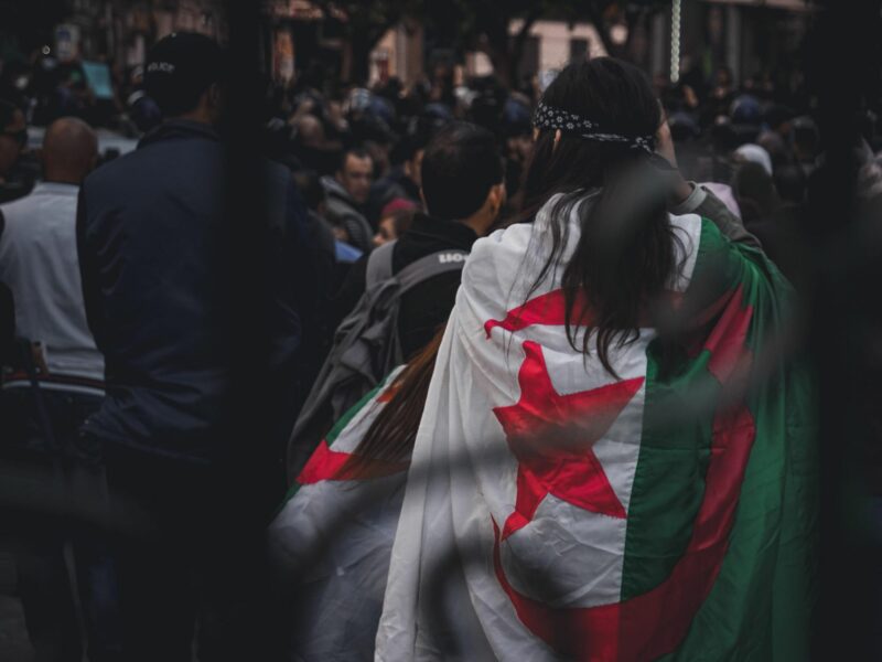 photo of a protester from behind with an Algerian flag