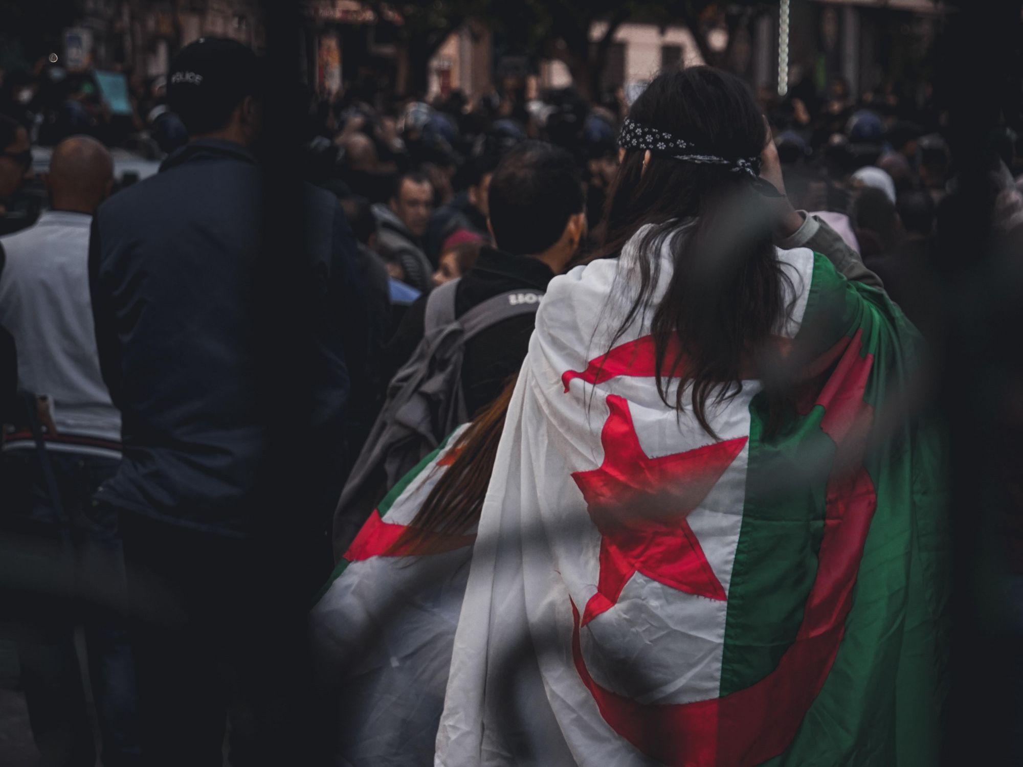 photo of a protester from behind with an Algerian flag