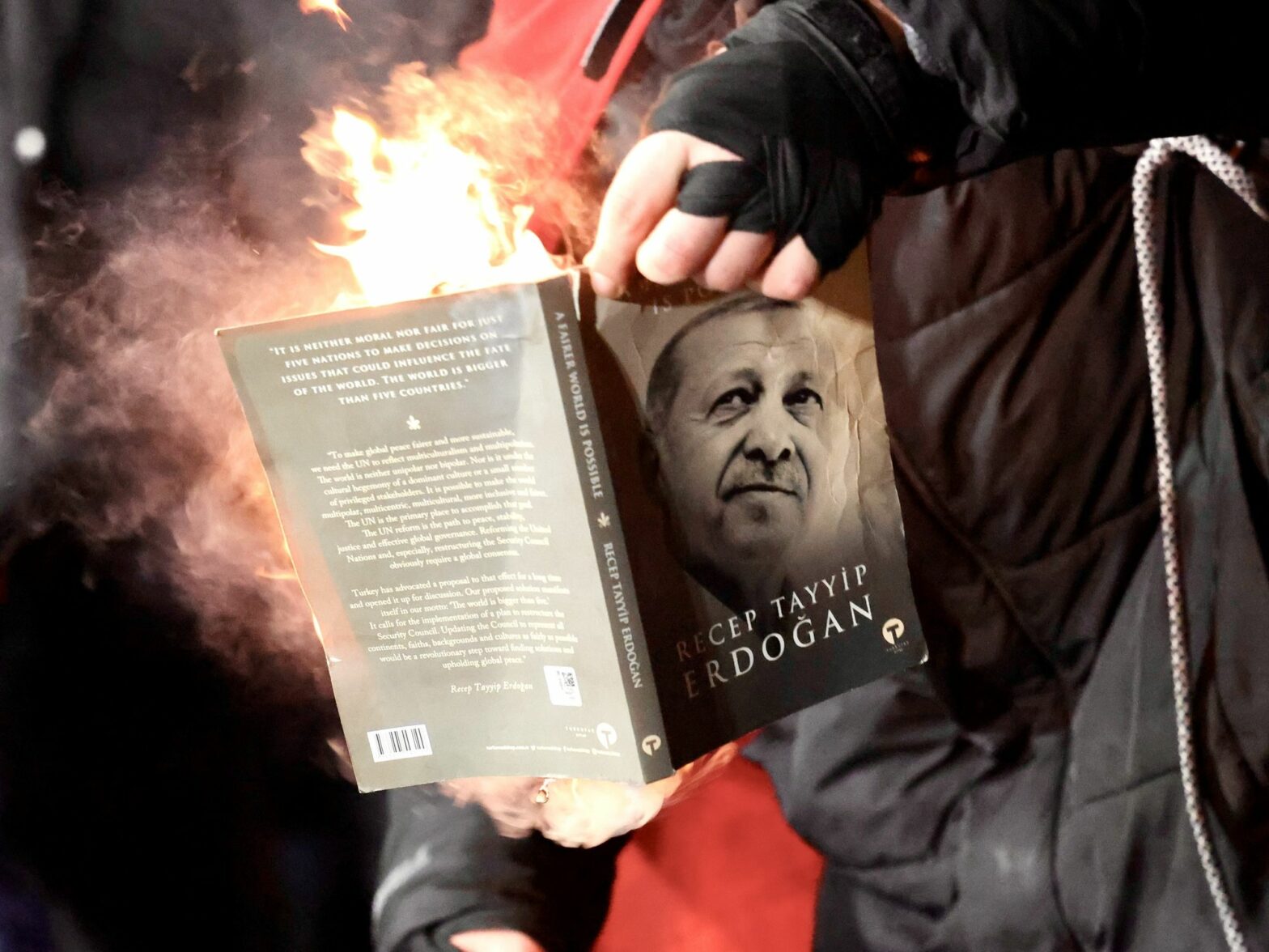 Photo of a protester lighting on fire a copy of a book with Erdogan's face on the cover, as part of protests in Istanbul on March 23.