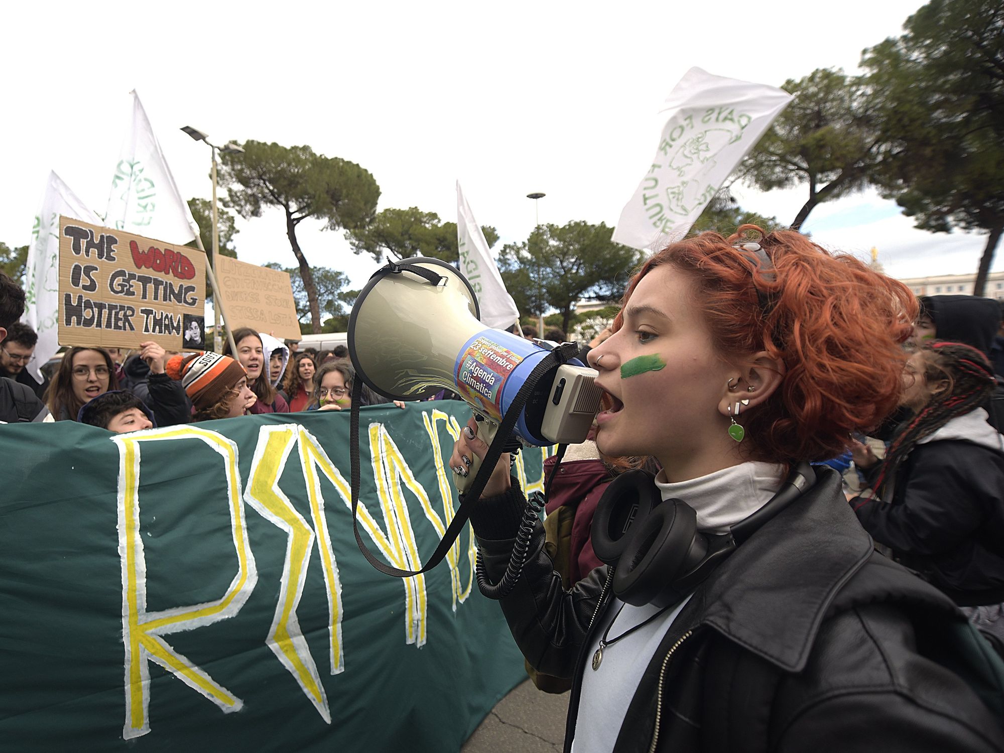 Photo of a protester shouting slogans through a megaphone during a climate protest in Rome.