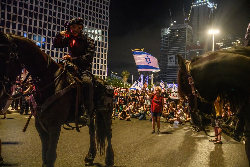 photo of a protestor waving the Israeli flag in front of mounted police officers during an anti-government demonstration this month in Tel Aviv.