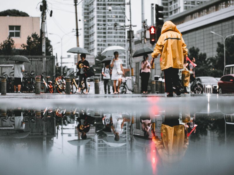 photo of a puddle and reflection of people walking in the rain