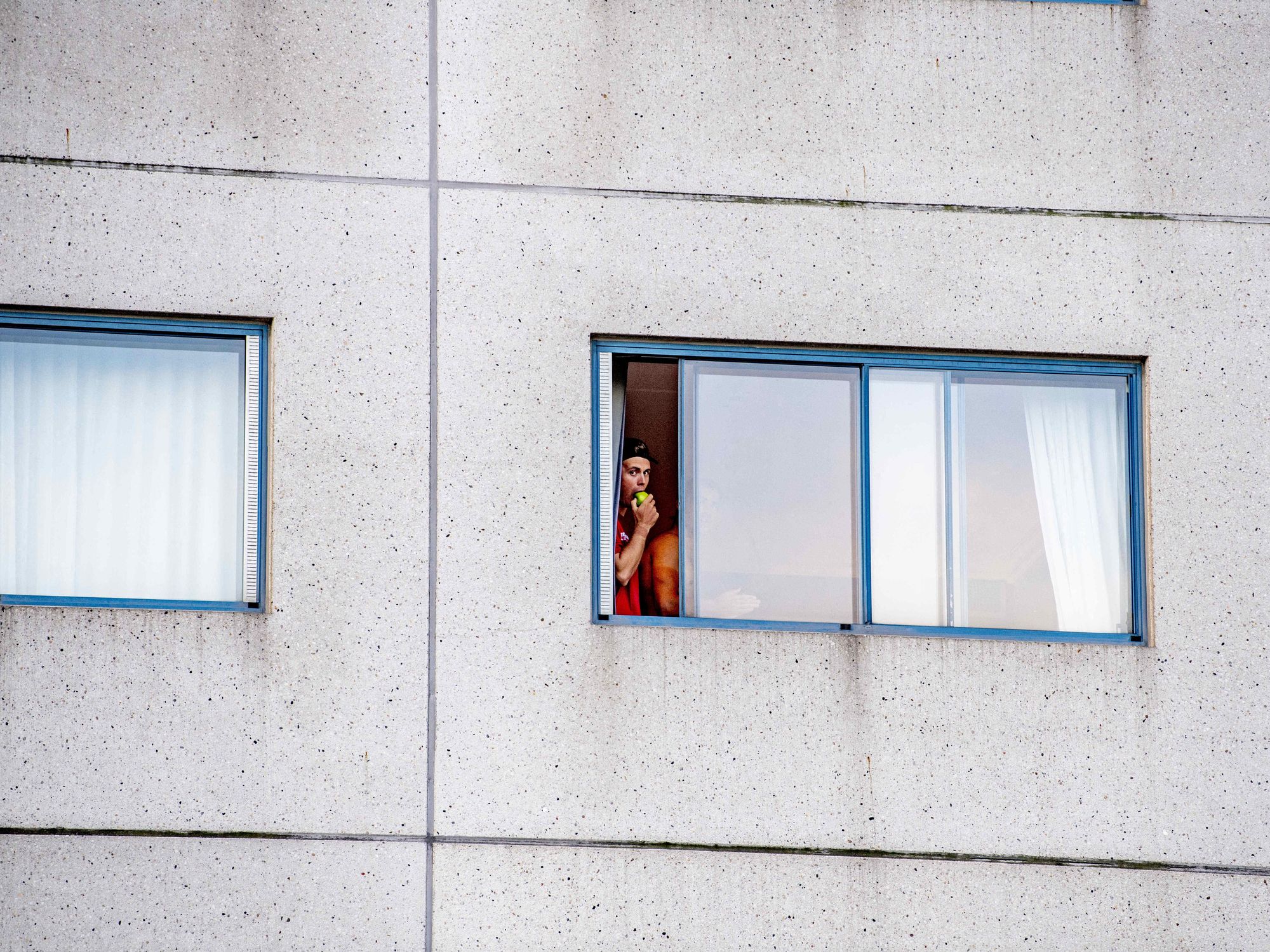 Photo of a quarantined traveler looking out the window of a hotel at Amsterdam's Schiphol airport