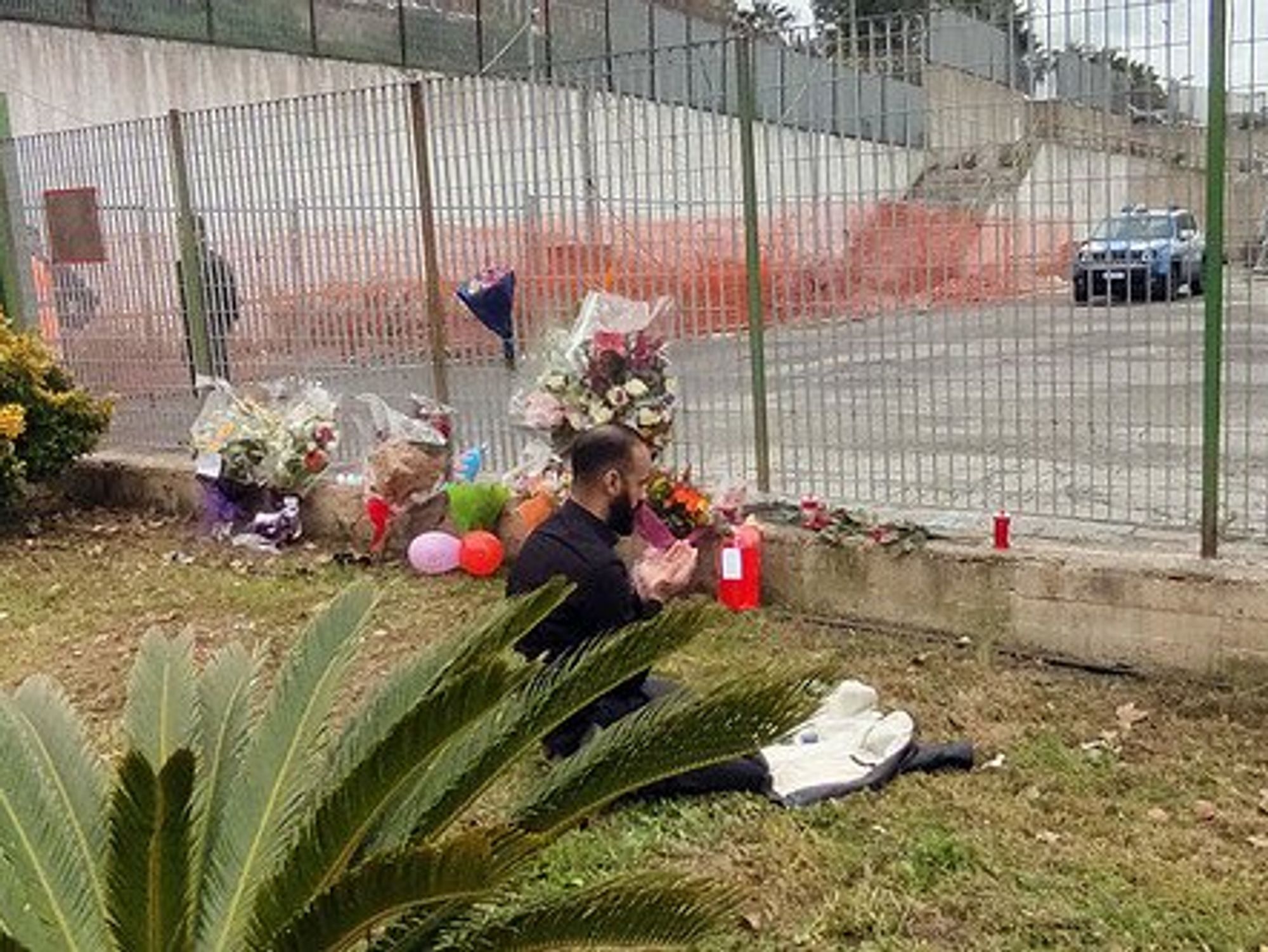 Photo of A relative of one of the victims praying in front of the Crotone's sports hall where the coffins have been momentarily placed