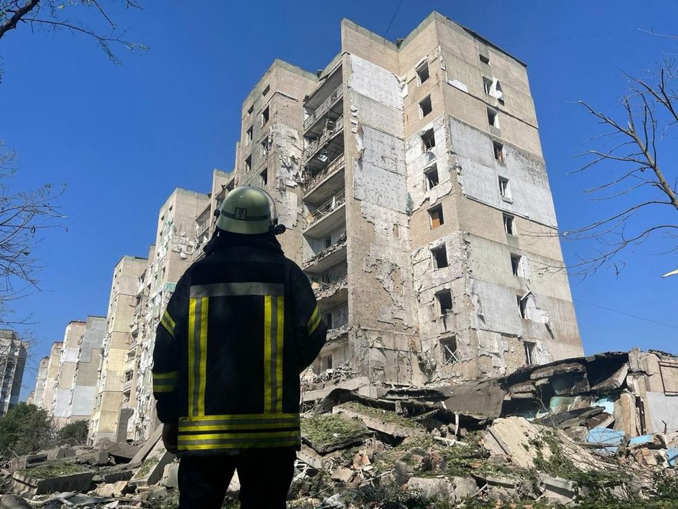 Photo of a rescuer stands in front of a destroyed building after deadly missile attack on Mykolaiv