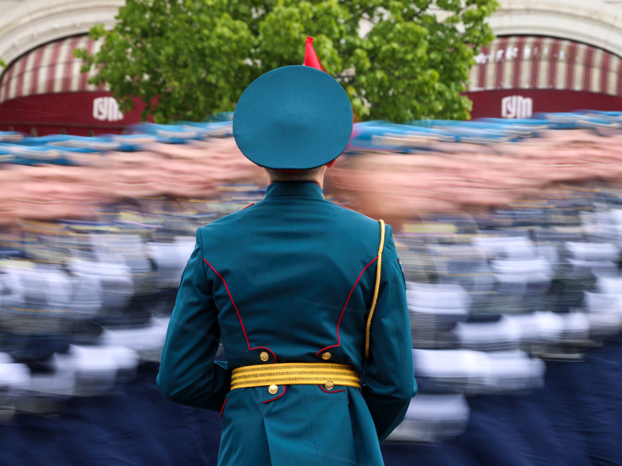 photo of a russian soldier from behind as the blur of a military parade passes.