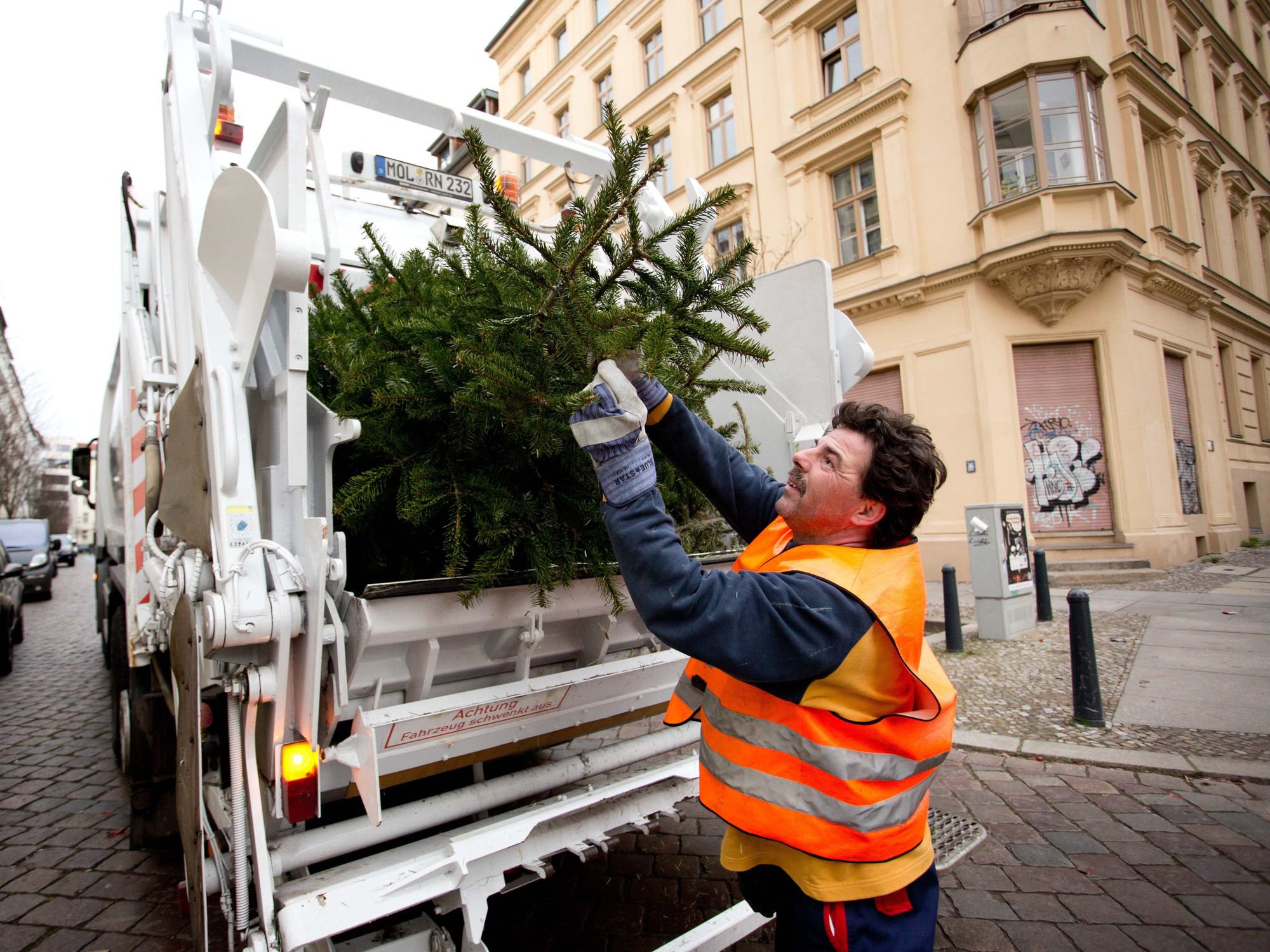photo of a sanitation worker throwing out a christmas tree