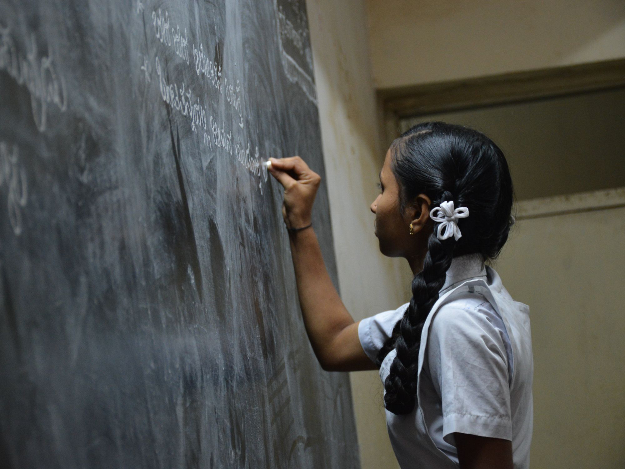 Photo of a schoolgirl writing on a blackboard