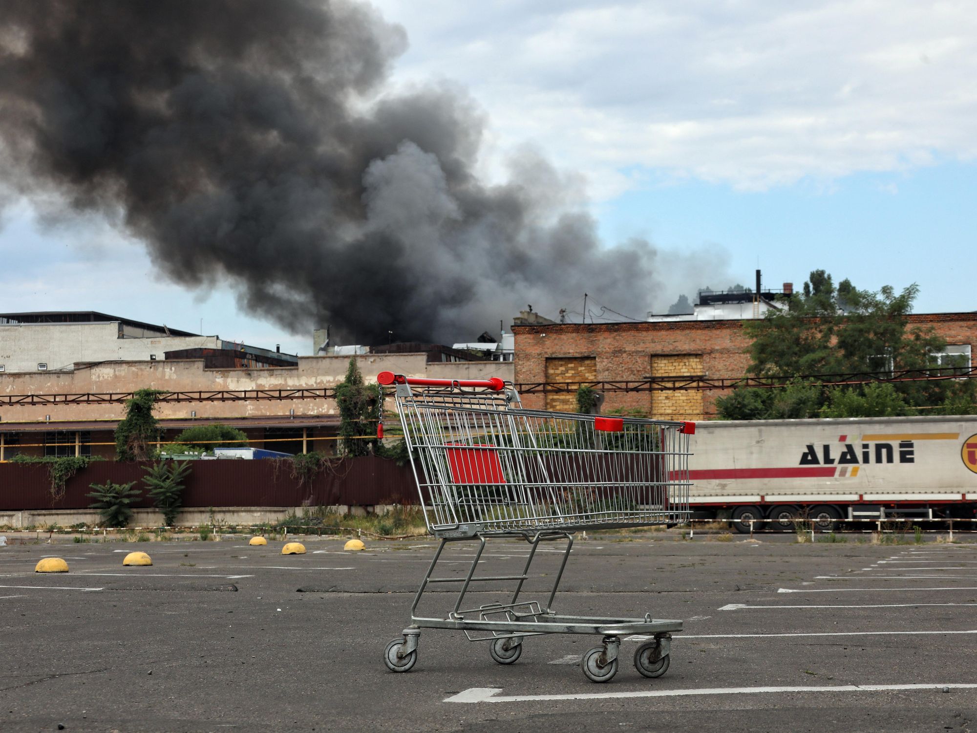 Photo of a shopping cart in a parking lot in Odessa with smoke in background