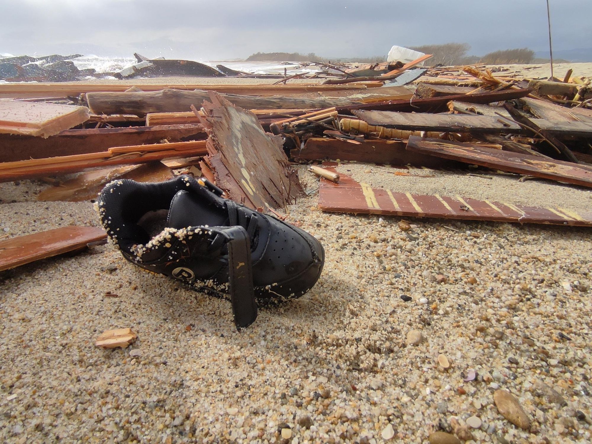 Photo of a show amid the remains of the boat after migrants washed ashore following the shipwreck.