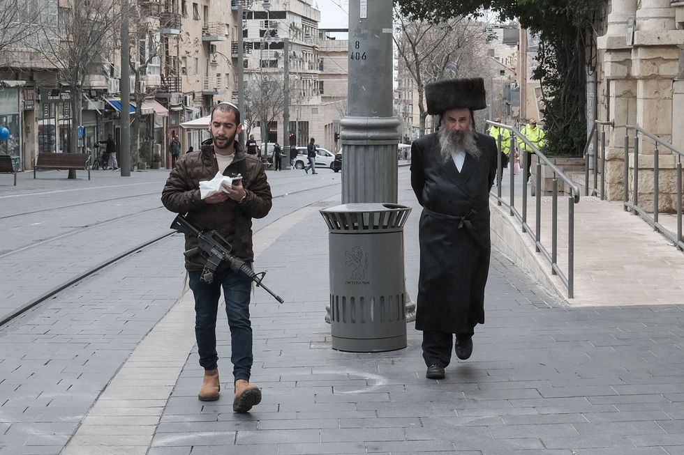 photo of a soldier and Orthodox jew walking on a sidewalk