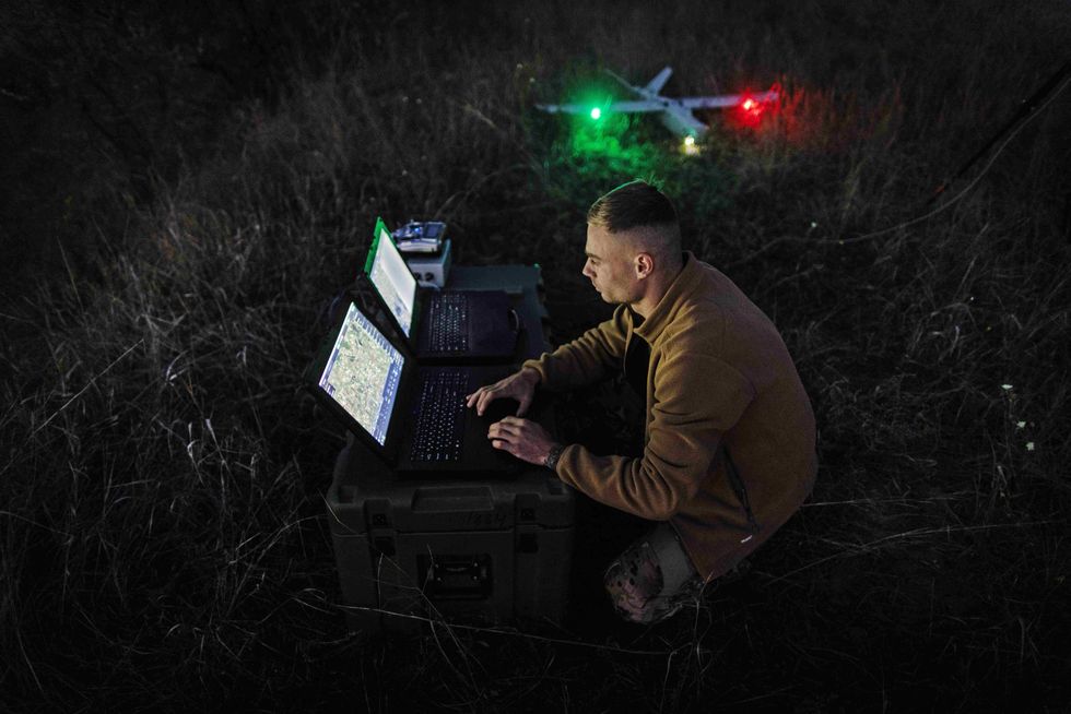 photo of a soldier at night checking his drone and computer