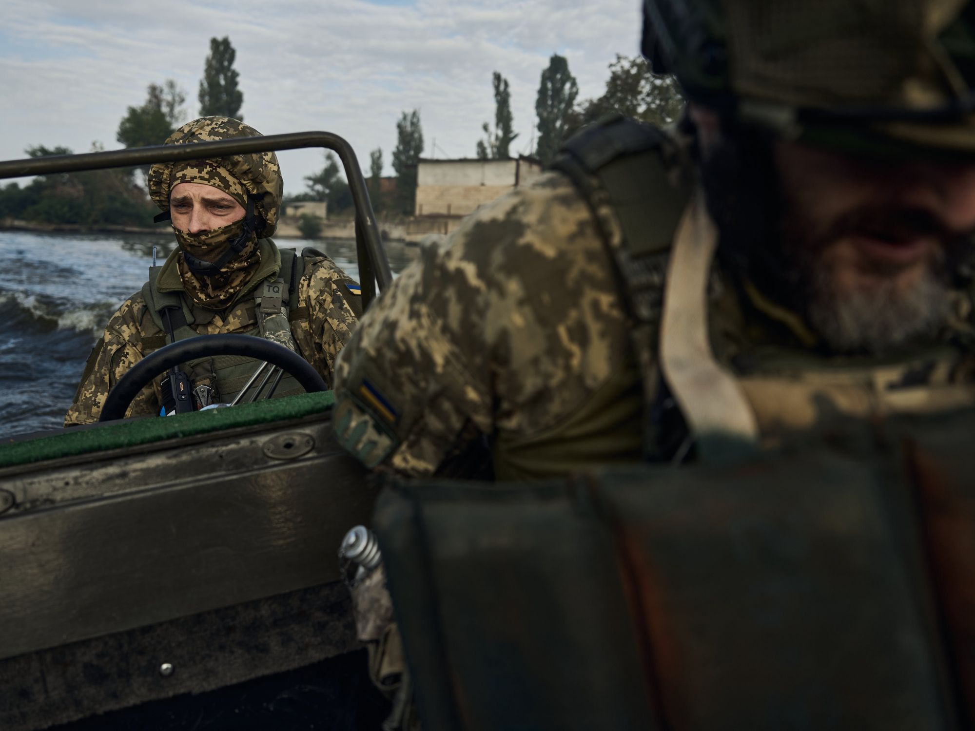 photo of a soldier driving a boat on a river