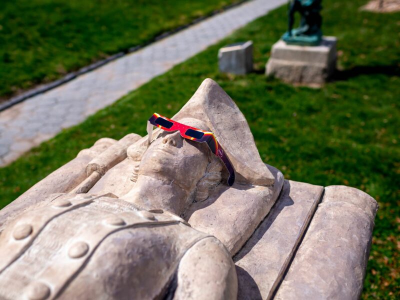 Photo of a statue of Margaret Cohen in New York with a pair of eclipse protective glasses on