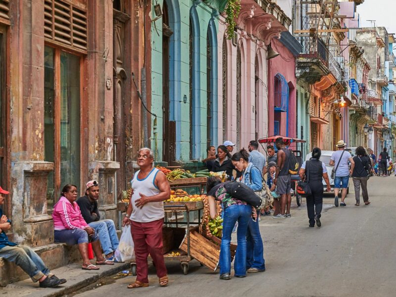 Photo of a street in Havana, Cuba with people stopping to buy fruits and vegetables